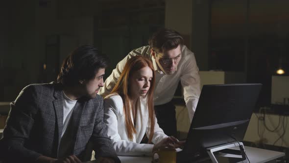 A Team of Office Employees Works Late at the Office at the Computer