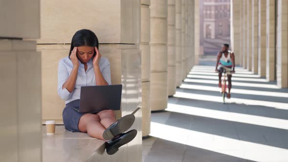 Tired Upset Young Lady Massaging Temples Working on Laptop Outside Office Center