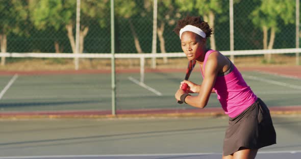 Video of focused african american female tennis player holding racket and hitting ball