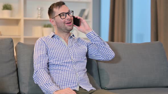 Cheerful Young Man Talking on Smartphone at Home 