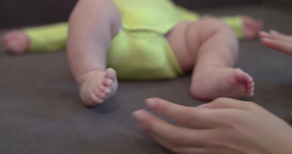 Mother's Hands Holds Baby's Legs at Camera