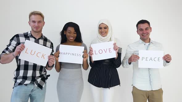 Multiethnic Men and Women Standing Near white Wall and Holding in Hands Posters with Written Words