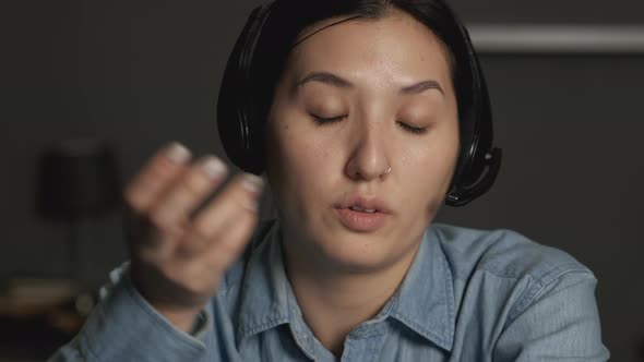 Close-Up of a Young Asian Woman in Headphones with a Microphone Communicating