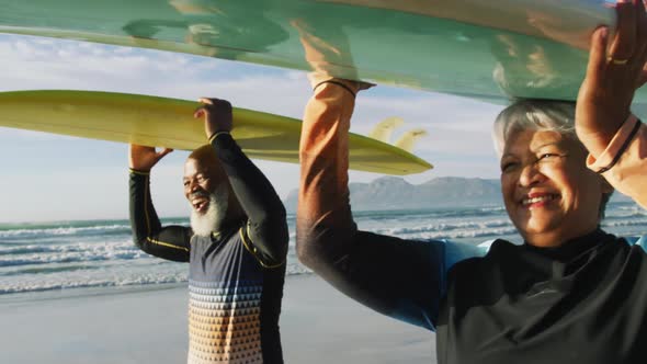 Senior african american couple walking with surfboards at the beach