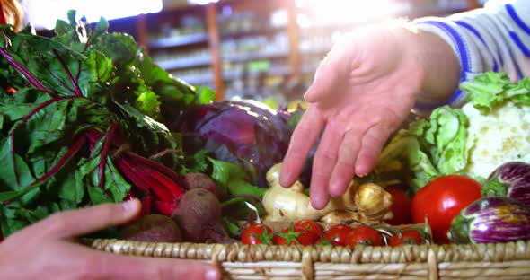 Male staff assisting woman in selecting fresh vegetables