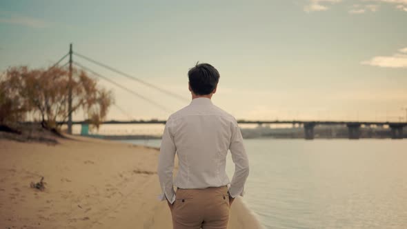 Man Walking On City Beach. Cheerful Romantic Guy In Sunglasses Walks On Sand And Dreaming.