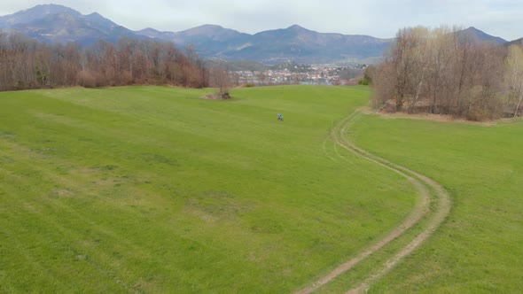 Aerial view: couple cyclist riding mountain bike in the countryside on the Alps