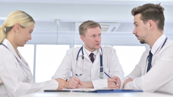 Senior Male Doctor Talking To Young Doctors in Office