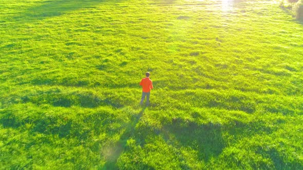 Flight Over Sporty Man Running at Perfect Green Grass Rural Meadow Offroad. Sunset in Mountain