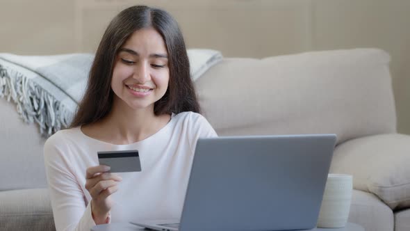 Happy Female Arabian Consumer Shopper Hold Plastic Banking Card Enter Numbers for Online Bank App