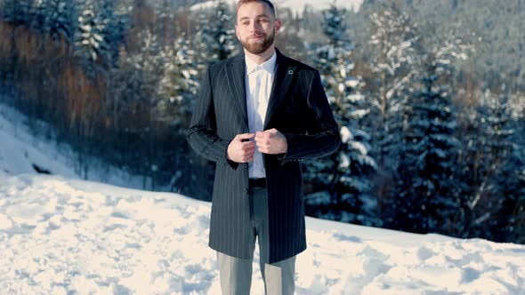 Groom on the Background of Snowcapped Mountains