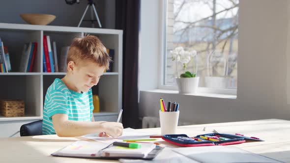 Boy is Doing  Homework at the Table. Cute Child is Learning at Home.