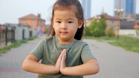 Pretty Asian Girl Holds Hands in Pray Gesture on Waterfront