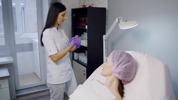 An experienced cosmetologist in sterile gloves prepares Botox injections for a woman