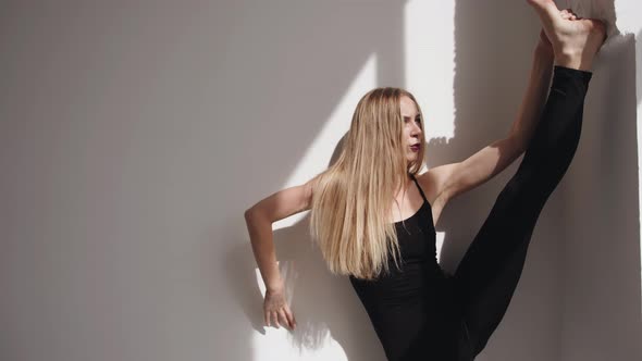 Smiling Young Girl Doing Stretching and Putting Her Leg on the Wall and Standing in a Vertical Split