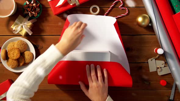 Woman Wrapping Christmas Gift Into Paper at Home