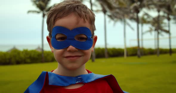 Beautiful Little Boy in the Superhero Costume Dressed in a Blue Red Cloak and the Mask of the Hero