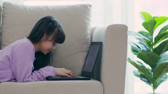 cute girl children using computer laptop on sofa online learning and meeting online