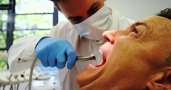 Dentist examining a male patient with tools