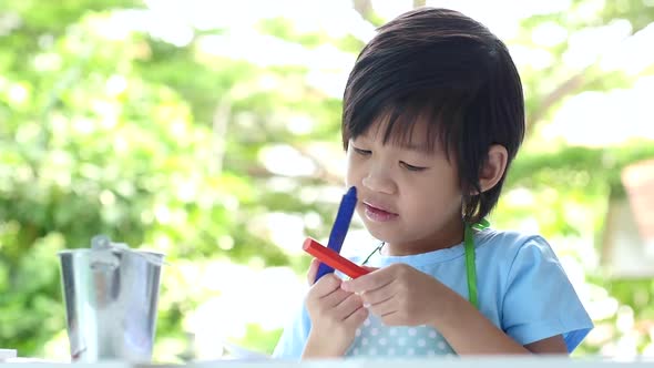 Cute Asian Child Drawing With Crayons On White Table