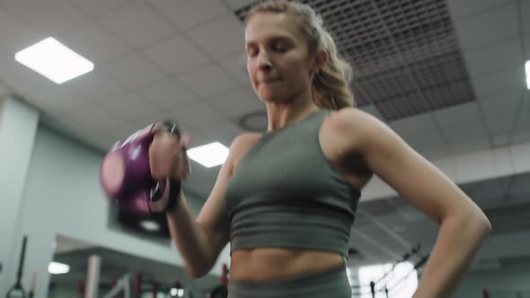 Young caucasian woman  exercising with kettlebells at a gym. Shot with RED helium camera in 8K.
