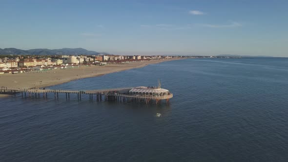 Pier reflecting over the Sea during a Breathtaking Sunset with Town and Hills on the Background