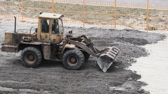 An Old Bulldozer on Rubber Wheels Works on Construction Site.