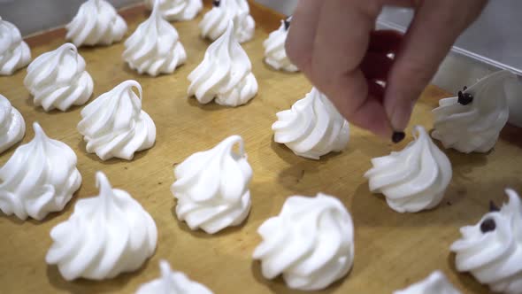Closeup of Chef Hand Decorating White Meringues Snack with Chocolate Chip in the Kitchen Factory