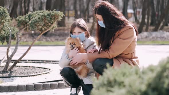 European Mother and Her Daughter Are Walking with a Dog During Quarantine in the Spring Park