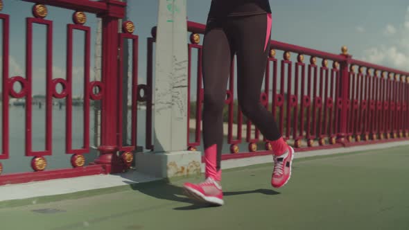 Fit Female Athlete Running Along Urban Bridge