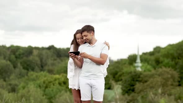 Couple In Love. Man And Woman Looking At Phone In Nature.