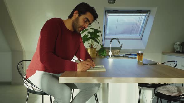 Man writing poetry journal notes in notepad book, morning creative home thoughts