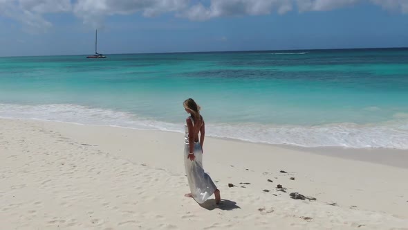 Woman in White Dress is Walking on a Tropical Beach Light Blue Ocean Water