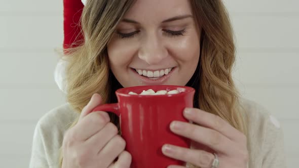 Young woman takes of sip from cup of hot cocoa