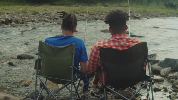 Rear View of Multiethnic Men with Fishing Rods Angling in Mountain River