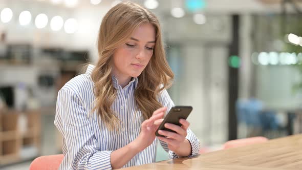 Serious Businesswoman Using Smartphone in Office 