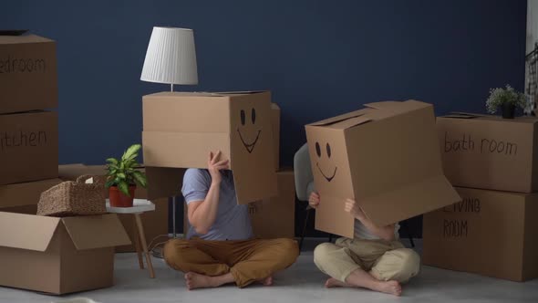 Happy Family Husband and Wife Remove Boxes with Painted Laughing Faces From Their Heads