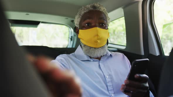 African american senior man wearing face mask pointing towards a direction while sitting in the car