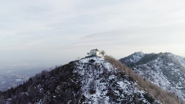 Moving Forward to Building or Church Over the Top of Snowy Mountain in Autumn or Winter at Sunset