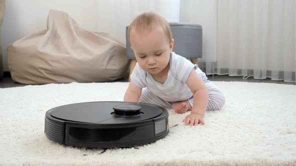 Cute Baby Boy Crawling on Floor and Chasing Robot Vacuum Cleaner Cleaning House