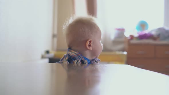 Joyful Boy Stands at Low Table and Mother Putting Sandglass