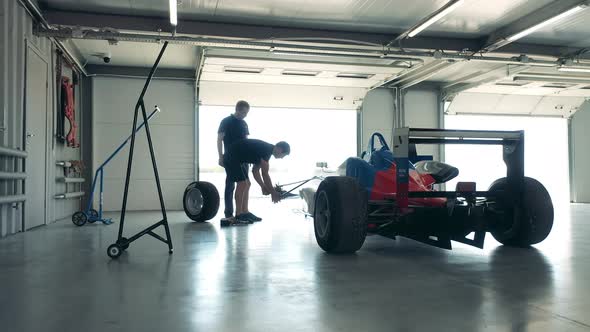 Male Experts are Fixing a Racing Car in the Garage