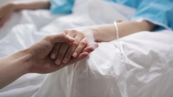 Man Holding Hand of Sick Woman in Hospital