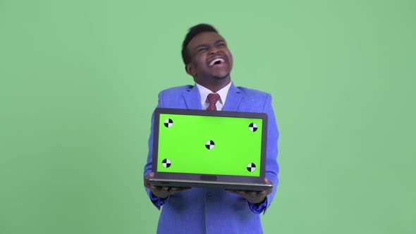 Happy Young African Businessman Showing Laptop and Looking Surprised