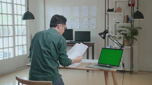 Designer Works On A Storyboard, Looks At His Sketches With Mock Up Green Screen Laptop