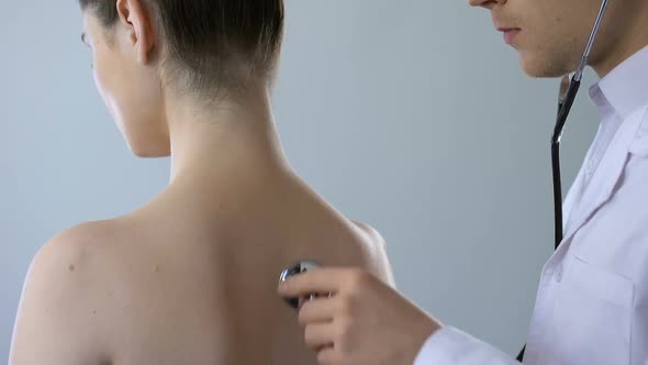 Physician Listening to Lungs With Stethoscope, Woman Breathing Heavily Back View