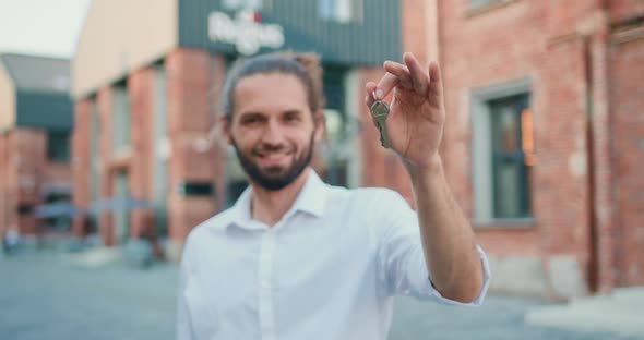 Handsome Smiling Bearded Man in White Shirt Holding Keys of New Flat, Looking Into Camera