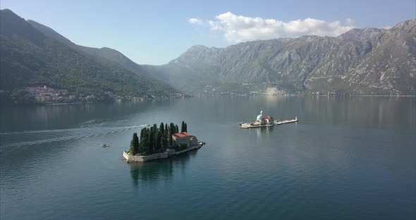 Aerial shot of man made islands in Montenegro with mountains in the distance.