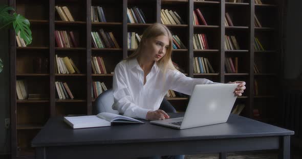 Business Woman Opens a Laptop and Takes a Notebook to Take Notes