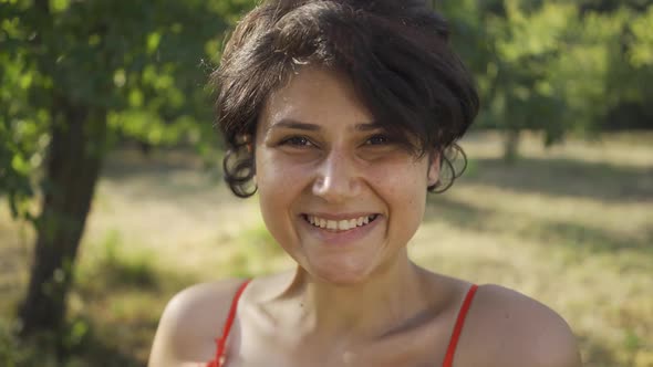 Portrait of Adorable Young Girl with Short Black Hair Standing in the Garden or Park with Her